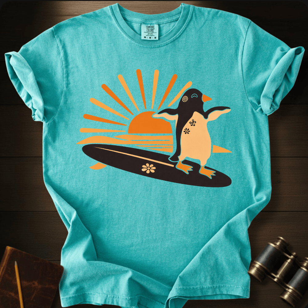 Full Sail Marine Sunset Surf penguin surfing graphic Comfort Colors t-shirt in chalky mint – cute penguin on surfboard with sunset design – front view
