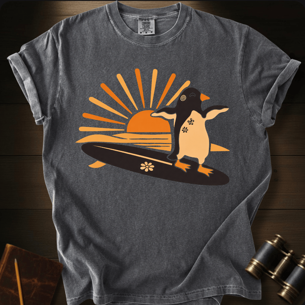 Full Sail Marine Sunset Surf penguin surfing graphic Comfort Colors t-shirt in pepper – cute penguin on surfboard with sunset design – front view