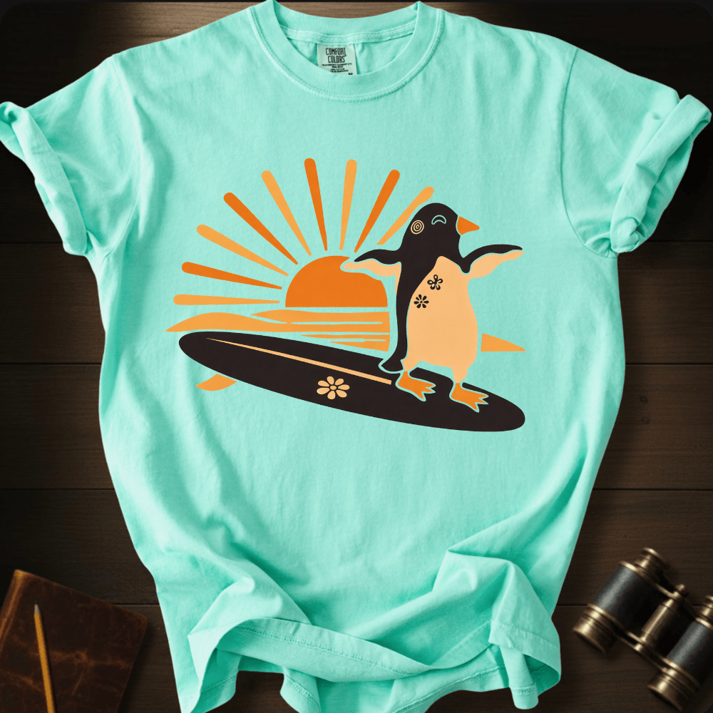 Full Sail Marine Sunset Surf penguin surfing graphic Comfort Colors t-shirt in island reef green – cute penguin on surfboard with sunset design – front view