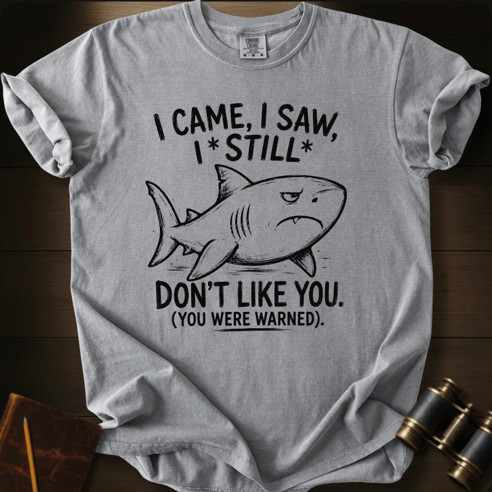 A light gray crewneck t-shirt with a black graphic of a shark and the text 'I CAME, I SAW, I*STILL* DON'T LIKE YOU. (YOU WERE WARNED)'.