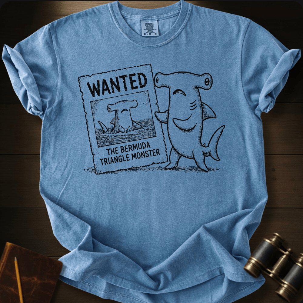Blue Comfort Colors tee with a cartoon hammerhead shark holding a 'Wanted: The Bermuda Triangle Monster' poster.