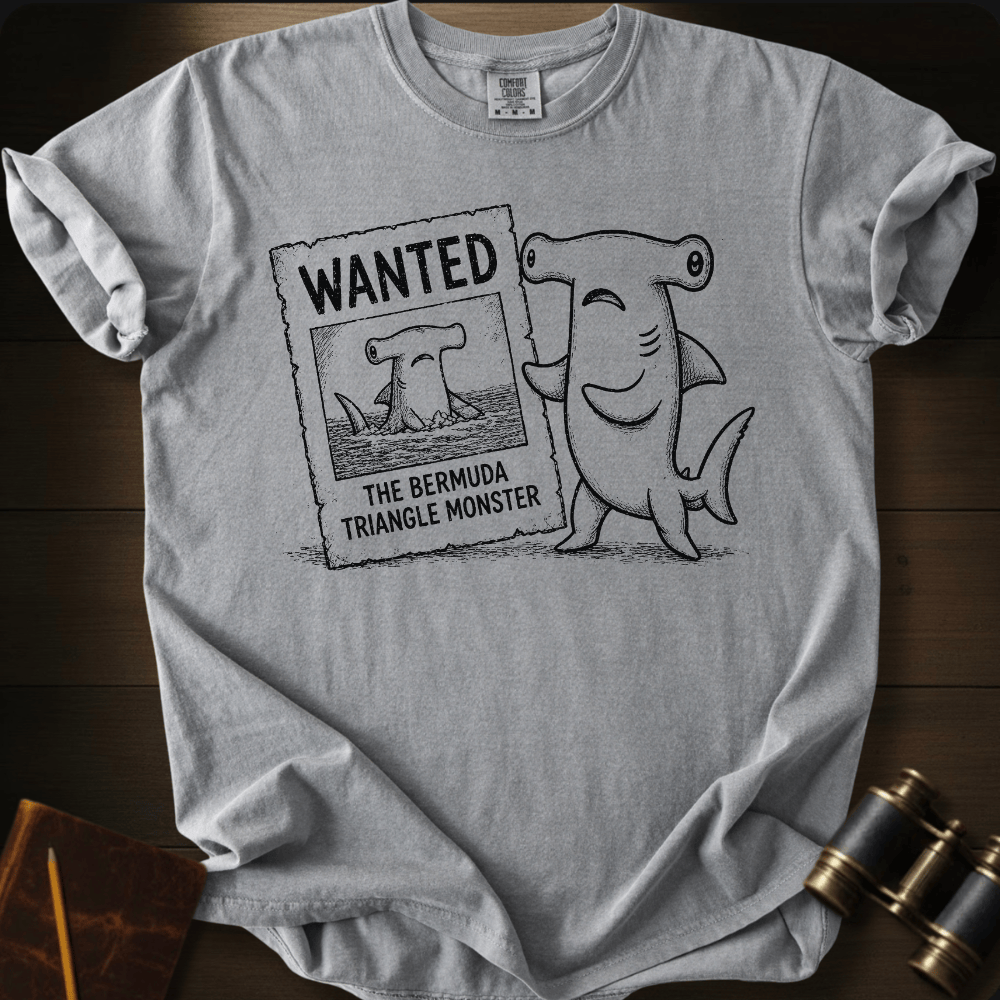 Grey Comfort Colors tee with a cartoon hammerhead shark holding a 'Wanted: The Bermuda Triangle Monster' poster.