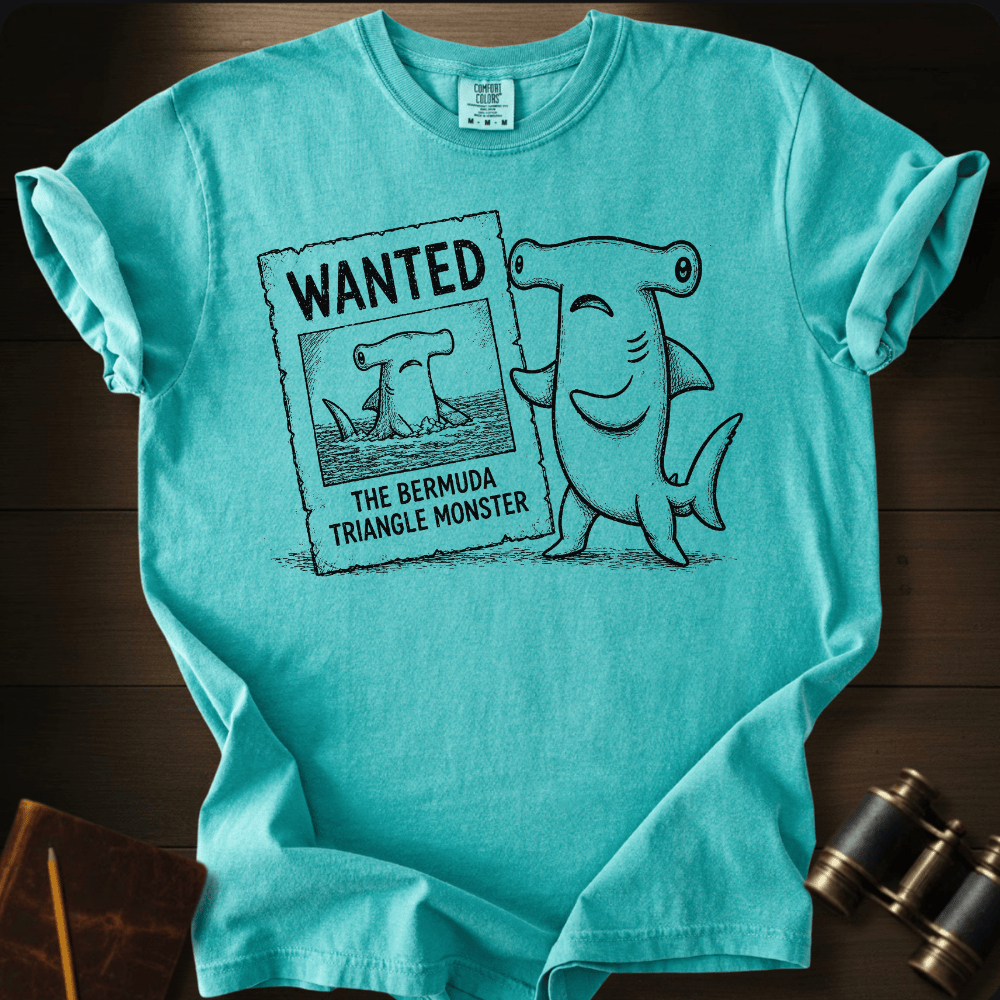 Teal Comfort Colors tee with a cartoon hammerhead shark holding a 'Wanted: The Bermuda Triangle Monster' poster.